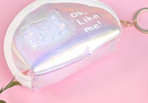A small iridescent zip pouch in a pastel pink keyring, displayed against a soft pink background.